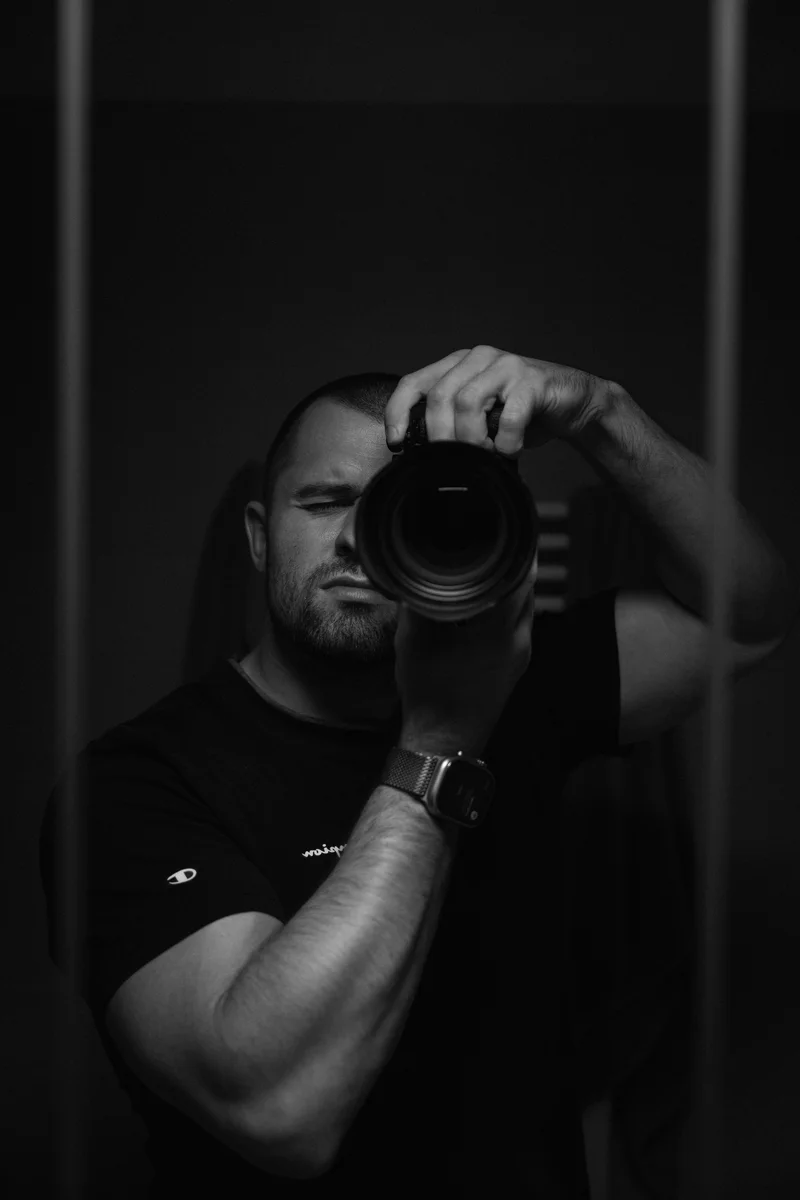 Lukáš Granatier s fotoaparátem u oka, odraz v zrcadle