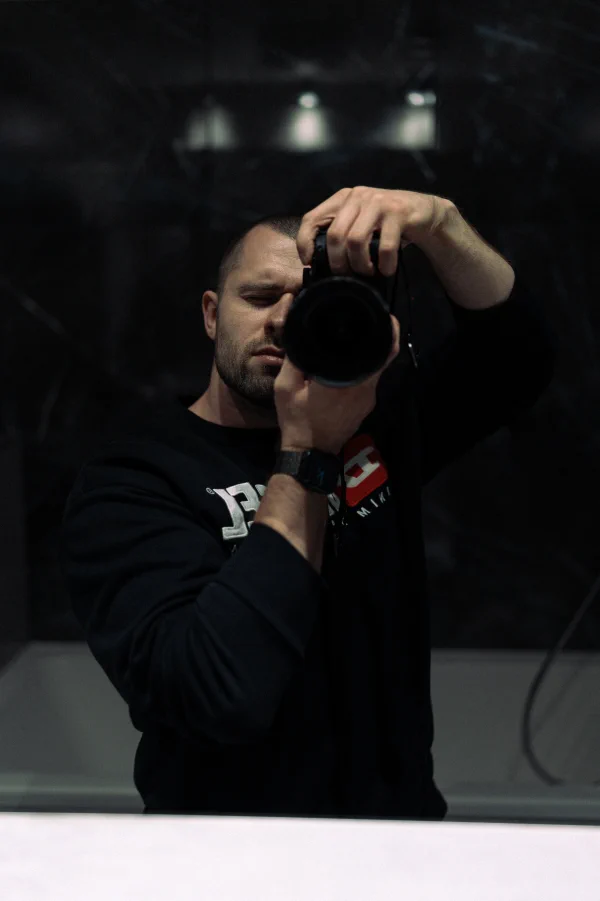Odraz fotografa s fotoaparátem u oka v tmavé lesklé ploše